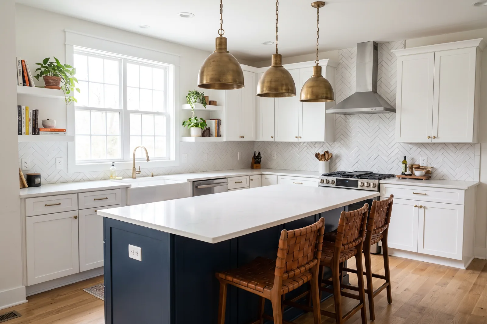 Completed kitchen remodel with a navy island, white shaker cabinets and brass pendant lighting