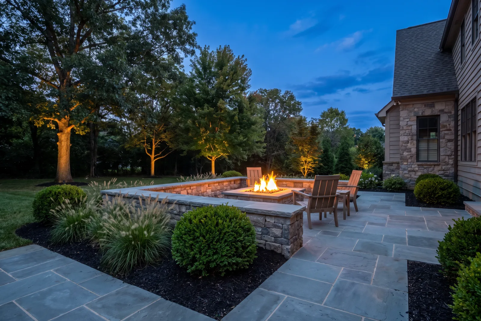A newly installed bluestone paver patio with a lit fire feature behind a Middle Tennessee home
